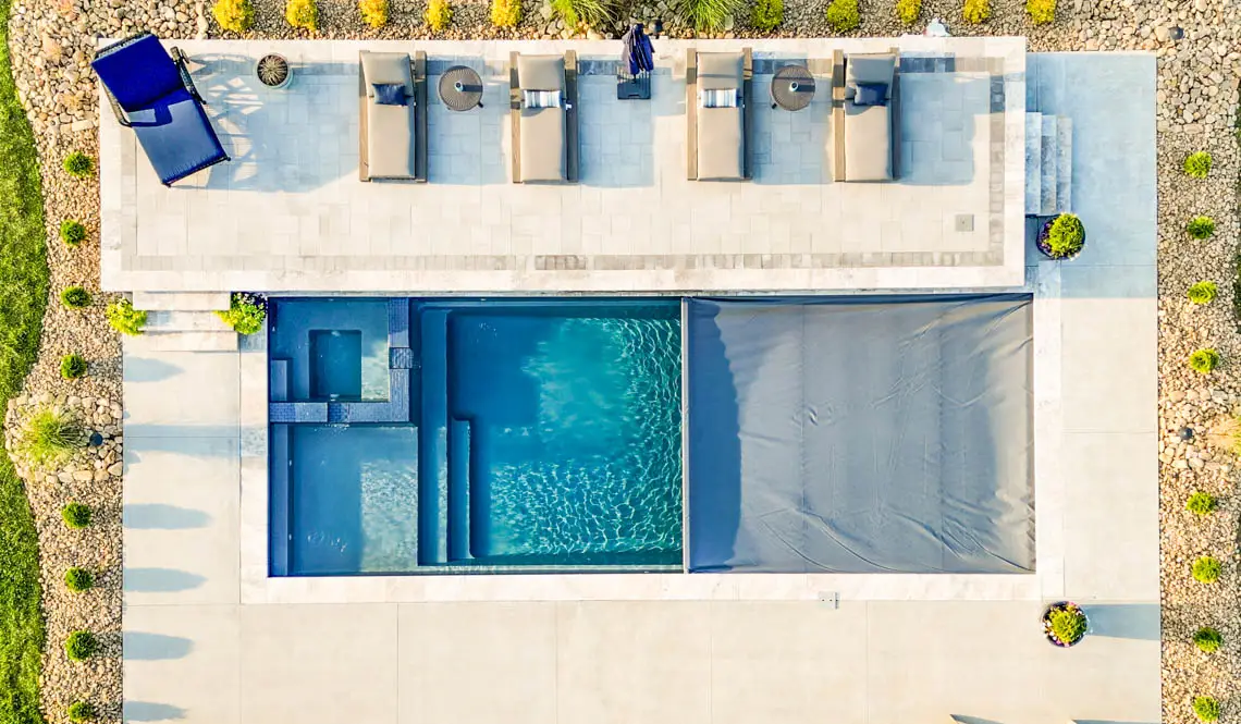 Leisure Pools Limitless inground fiberglass swimming pool with built-in spa deck in Silver Grey